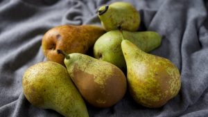 A close-up view of ripe and fresh pears displayed on soft gray fabric, showcasing their natural texture and color.